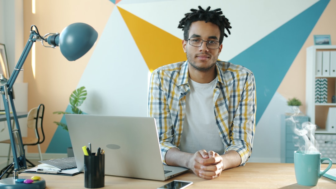 Man sitting at desk with laptop and steaming mug.